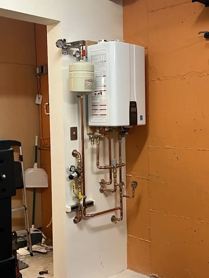 Plumbing technician inspecting water heater connections in Ridgway